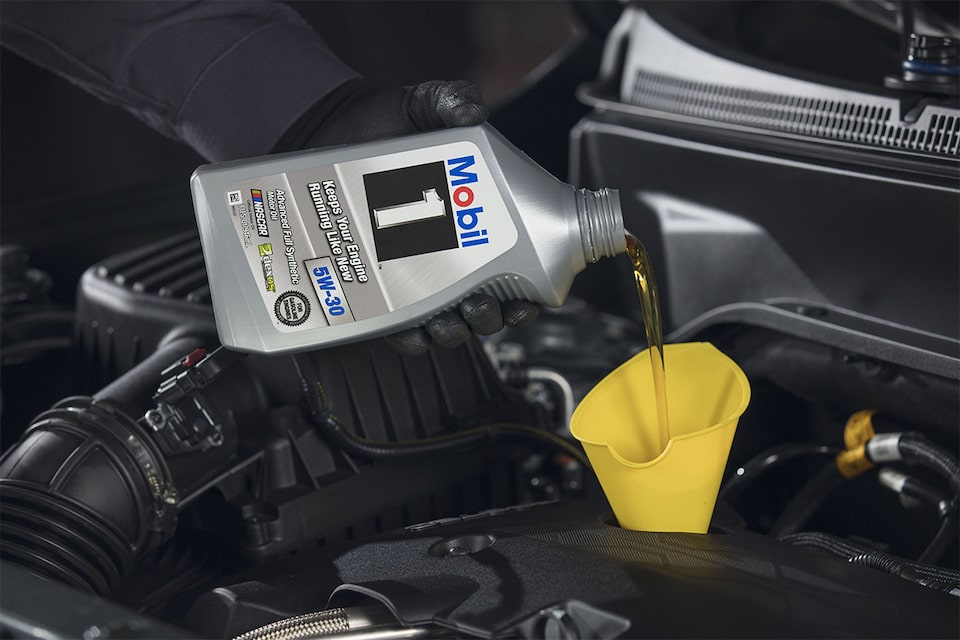 Certified Service technician refills vehicle with Mobil 1™ motor oil